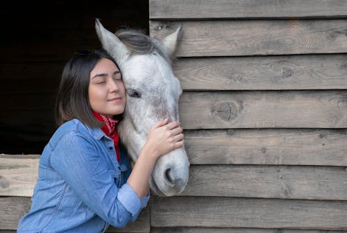 A Woman in Blue Jacket Hugging a Horse