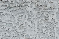 Cracked gray stucco wall with cracked surface