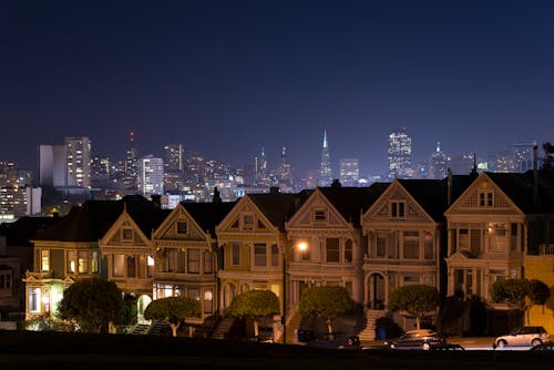 Illuminated Suburban Street with City Skyline in Background 