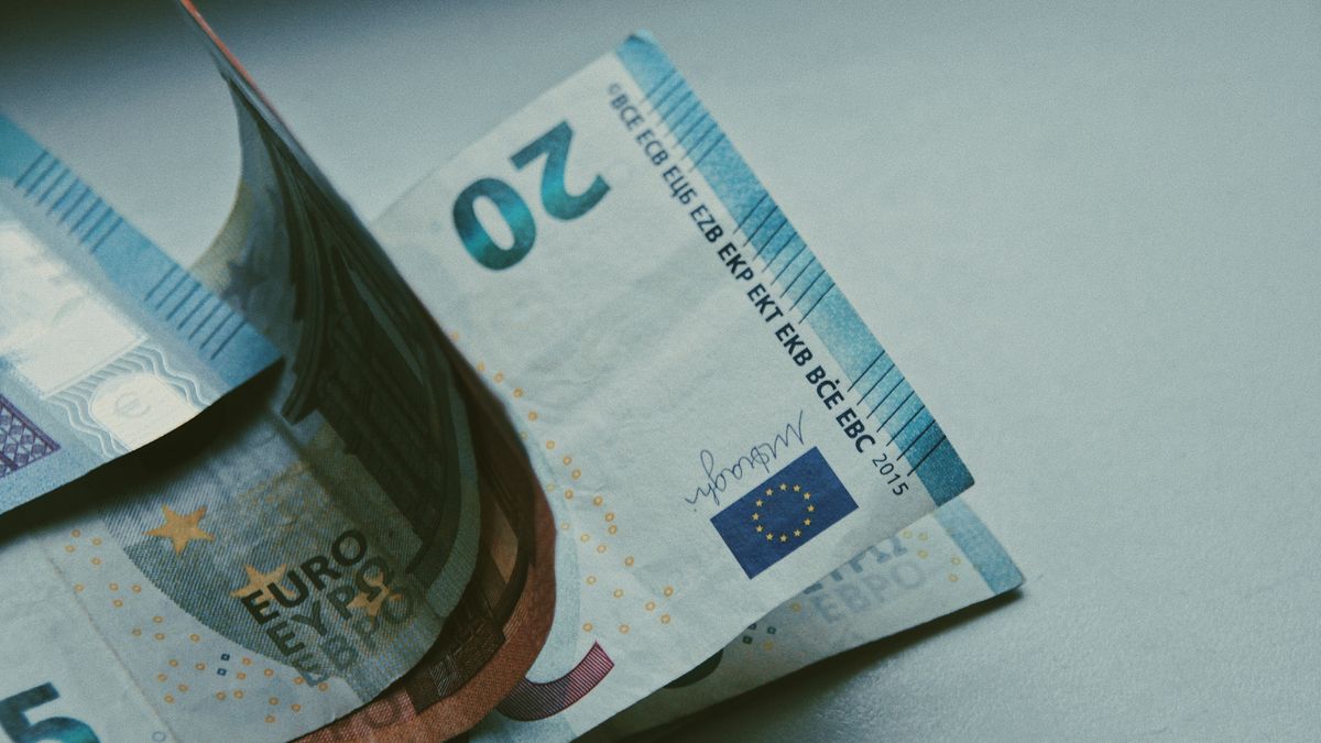 Detailed close-up of Euro banknotes on a white surface, focusing on currency design.