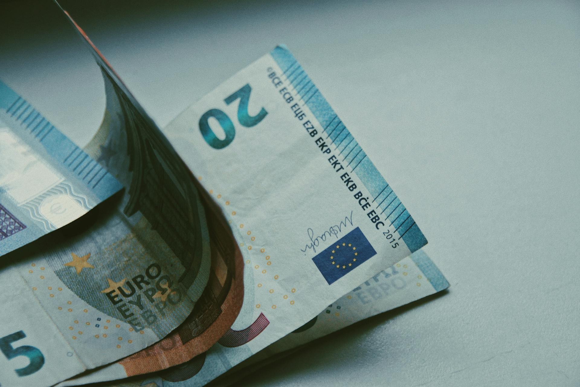 Detailed close-up of Euro banknotes on a white surface, focusing on currency design.