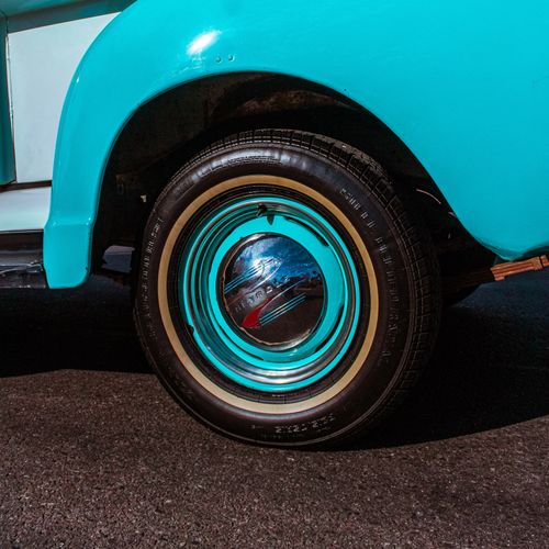 Free Close-up of a vintage car wheel with a turquoise fender, showcasing classic automotive design. Stock Photo