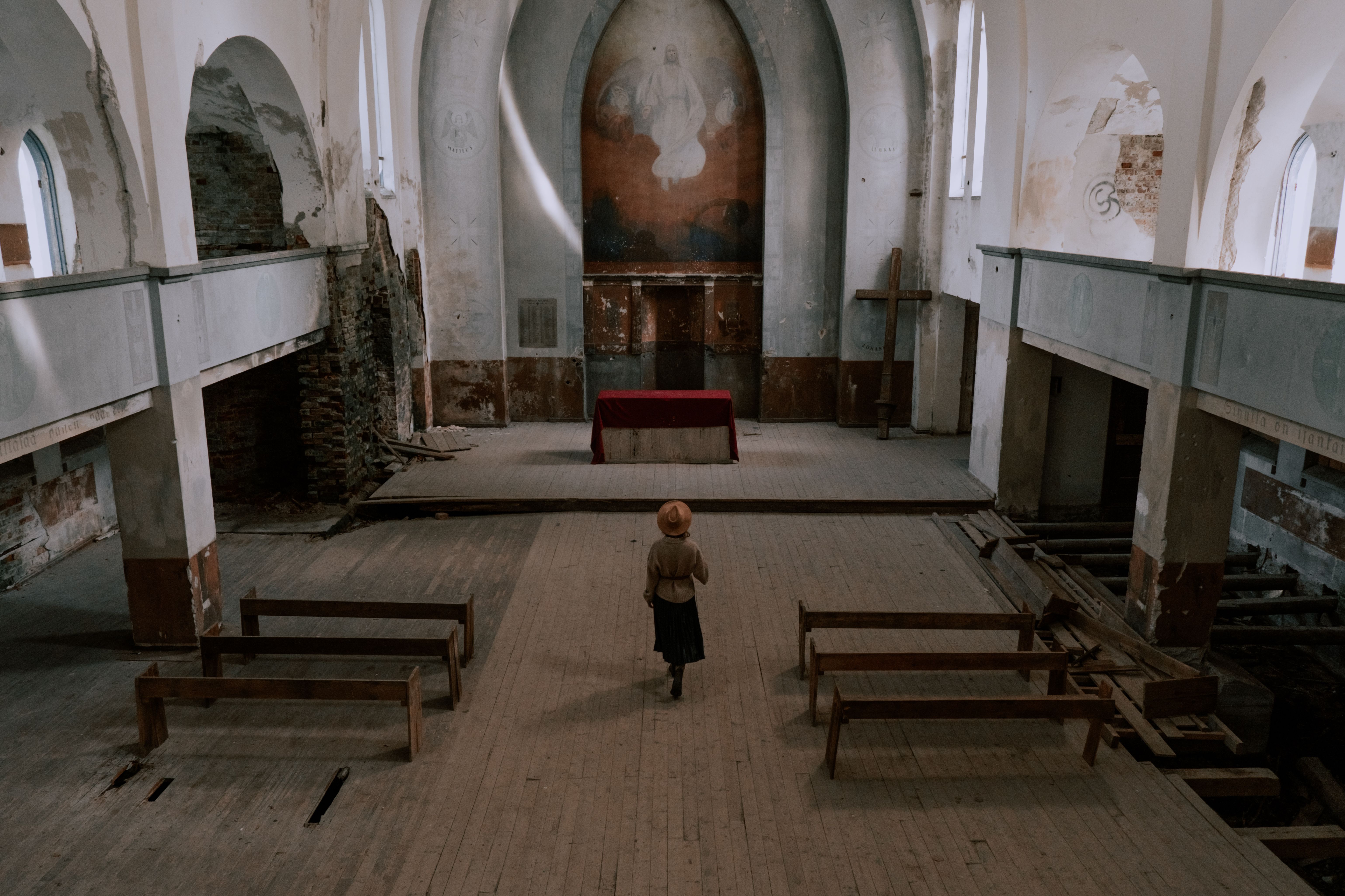 A woman stands in an abandoned church, capturing religious architecture and serenity.