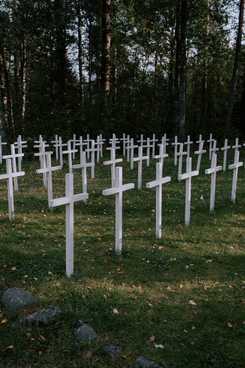Free Peaceful forest cemetery with white crosses on a grassy field during daytime. Stock Photo