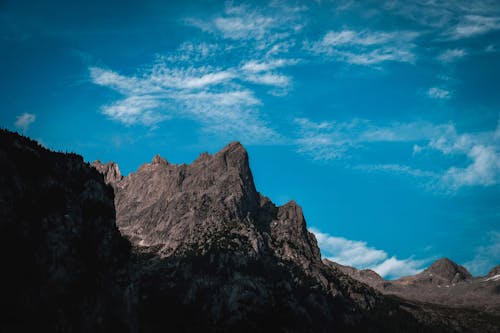 Majestic scenery of bright blue sky with white clouds floating over rough rocky mountain range on sunny day