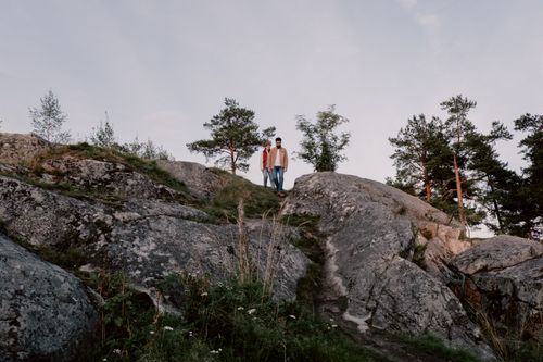 Free A couple walking together on large rocks under a blue sky during sunset. Stock Photo