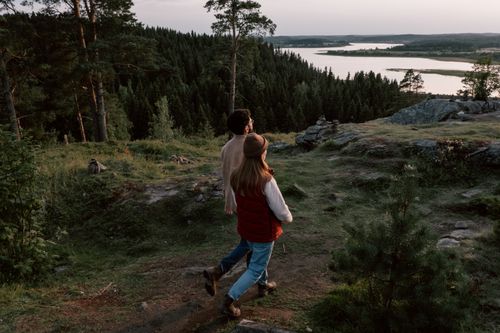 Free A couple explores a tranquil forest with a scenic river view, encapsulating nature's peaceful beauty. Stock Photo