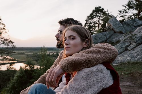 Free A young couple embracing while enjoying a serene evening in the countryside, surrounded by nature. Stock Photo
