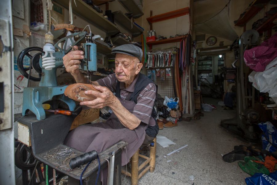 A cobbler at the workbench repairing a shoe by hand