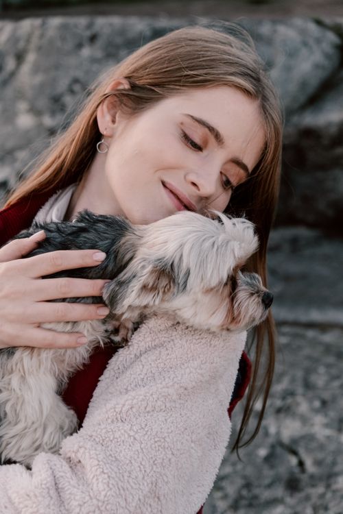 Free A caucasian woman lovingly embraces her small dog outdoors, showcasing a warm companionship. Stock Photo