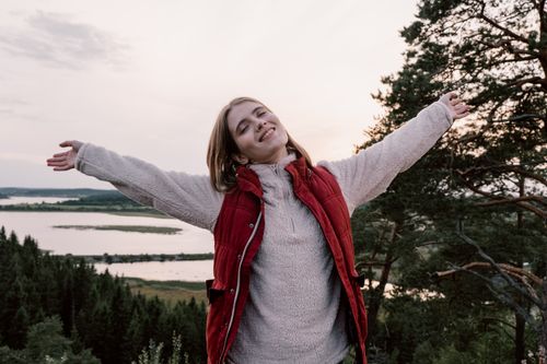 Free Woman enjoying freedom in a scenic landscape with open arms. Stock Photo