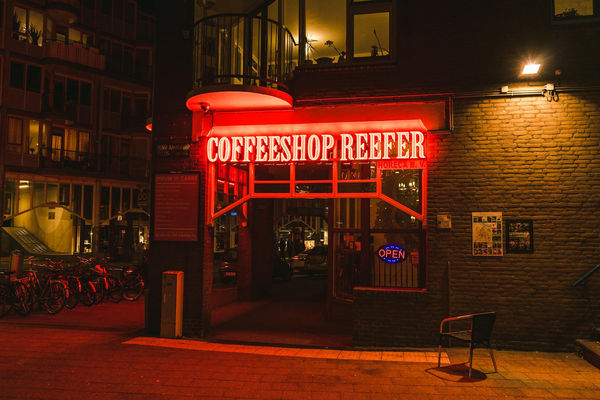 Nighttime view of Coffeeshop Reefer's vibrant neon entrance in Amsterdam, Netherlands.