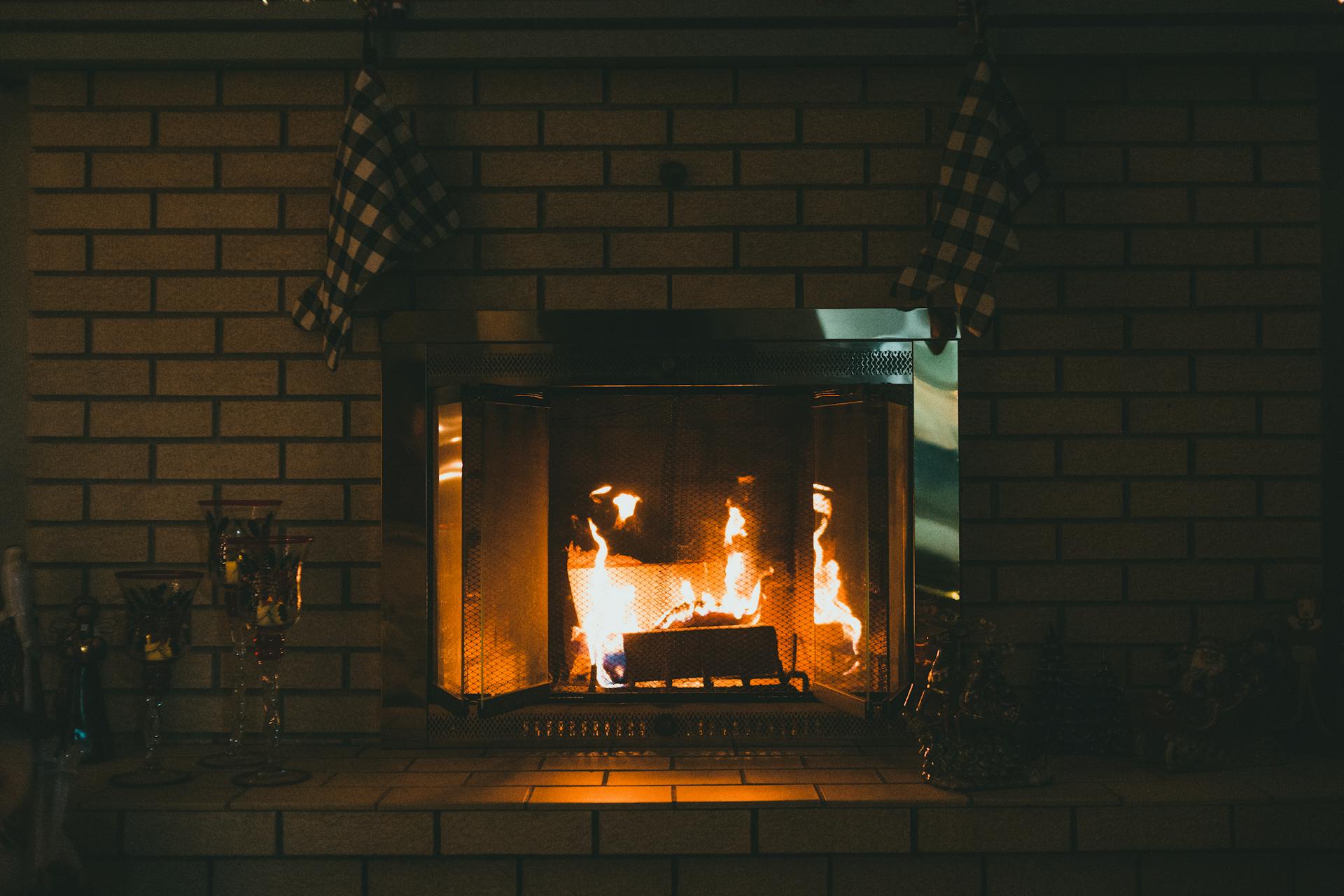 Fireplace with burning fire against glass candlesticks at home