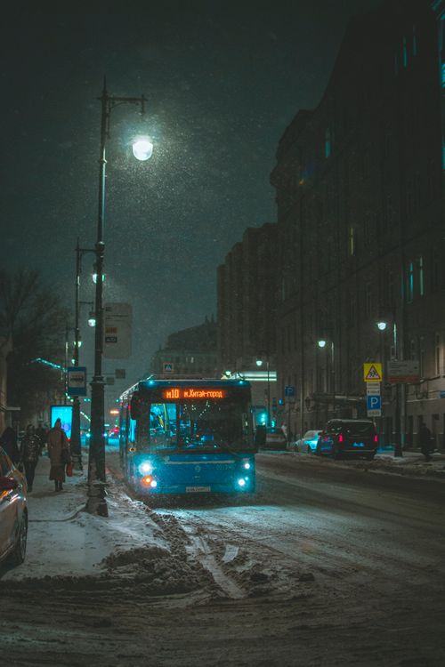 Free Winter night scene in Moscow with a blue bus and illuminated street, creating a moody urban atmosphere. Stock Photo