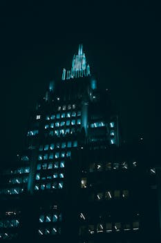 A dramatic night view of a modern skyscraper in Moscow, Russia, illuminated with striking blue lights.