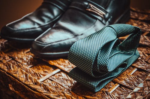 Free Man's Black Leather Shoes Near to Green and White Spotted Tie Stock Photo