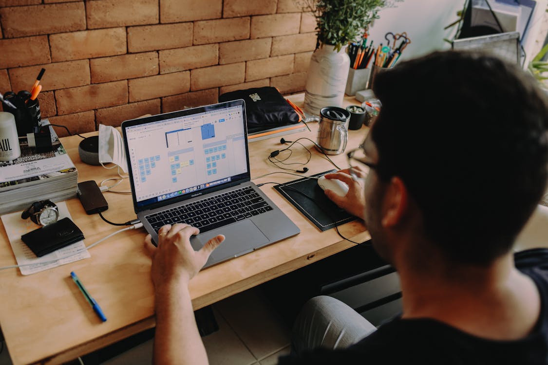 Free Person Using Laptop on Wooden Surface Stock Photo
