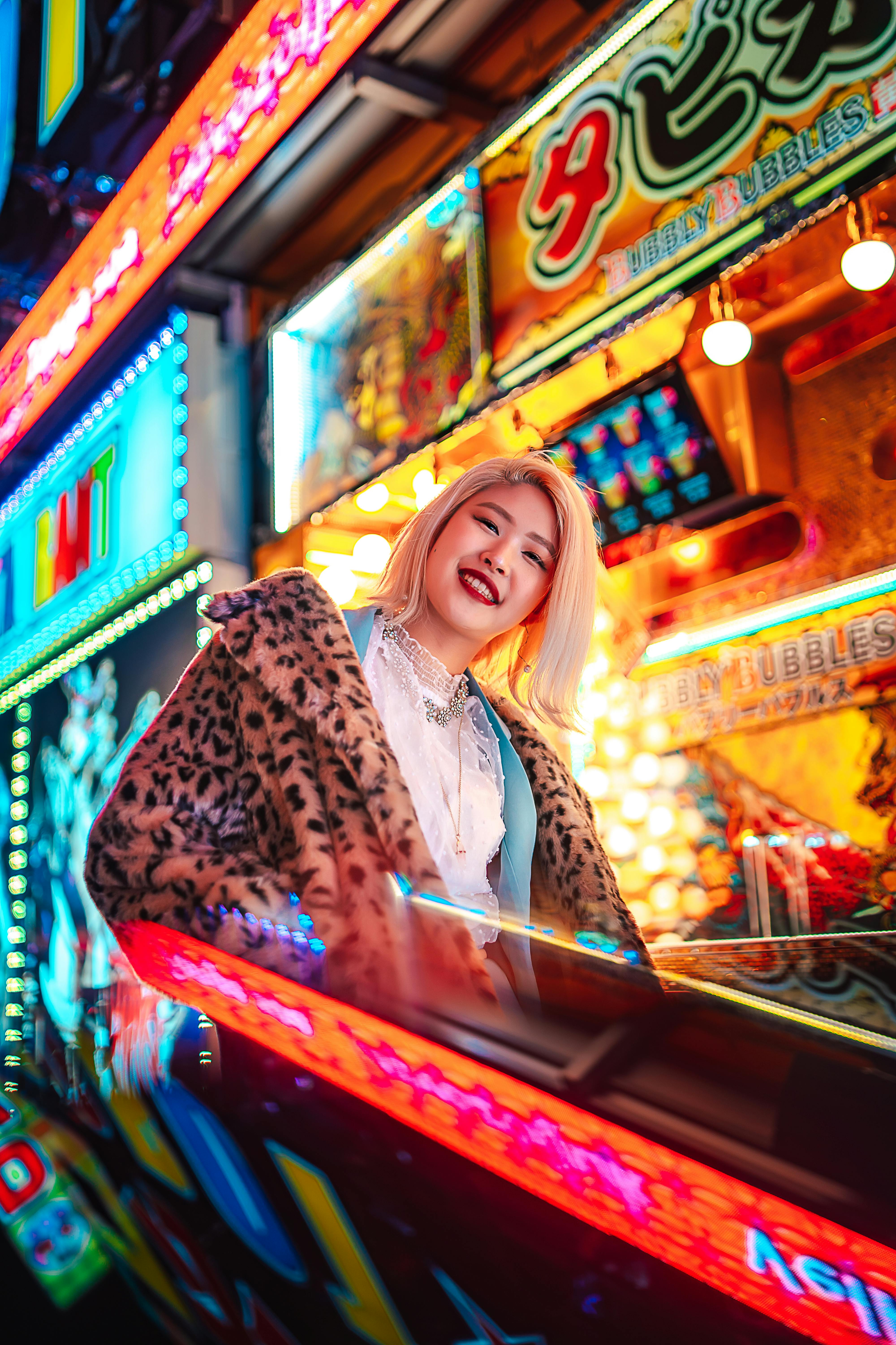 Stylish woman posing with neon city backdrop, showcasing urban street fashion vibrancy.