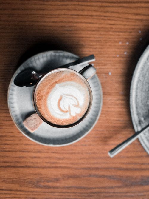 Free A beautifully crafted latte with latte art, captured from above on a rustic wooden table. Stock Photo