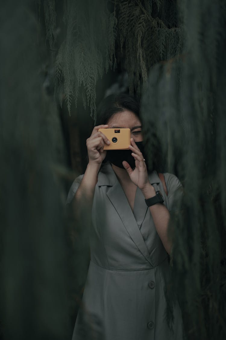 Faceless Woman Taking Photo On Film Camera Near Trees