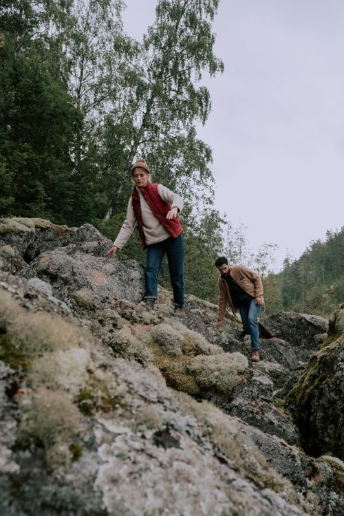 Free Two adults hiking over rocks in a lush forest area, showcasing adventure and nature. Stock Photo