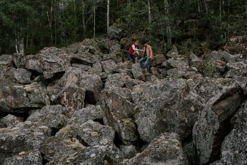 Free A couple exploring a rugged rock terrain amidst a lush forest landscape. Stock Photo