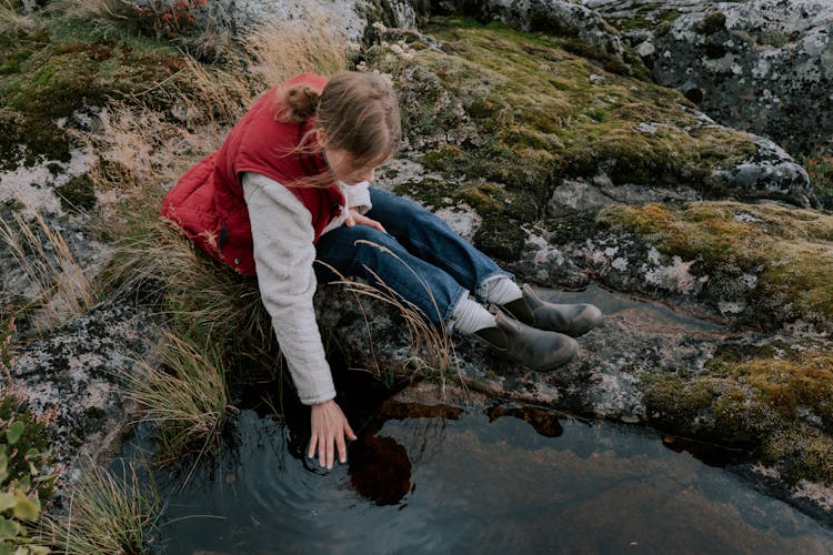 Woman In Red Jacket Touching Water