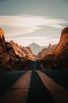 A breathtaking view of a straight road through rugged desert mountains during sunset in the Valley of Fire, Nevada.