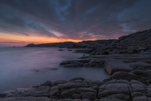 Rocky Coast at Sunset and Fog Over the Water Surface