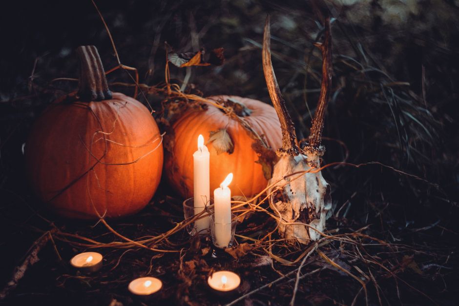 Spooky Halloween scene featuring pumpkins, candles, and a skull amidst a dark, eerie setting.