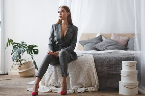 Free Businesswoman in stylish suit sitting on a bed with modern decor for a professional look. Stock Photo
