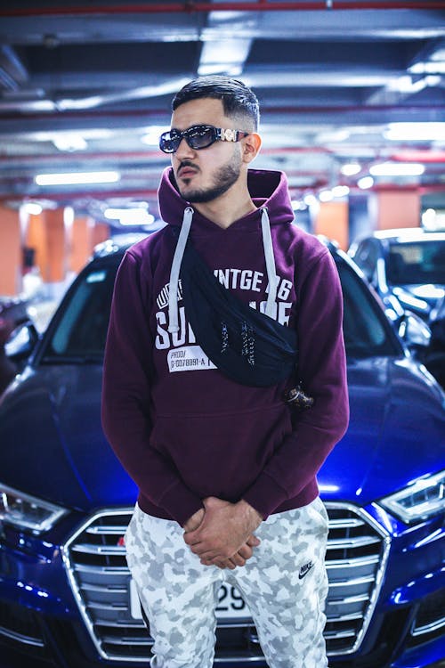 Free Man in Maroon Hoodie Standing Near Cars Stock Photo