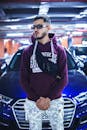 Man in Maroon Hoodie Standing Near Cars