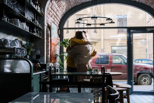 A couple embraces warmly inside a stylish café, capturing a moment of affection.