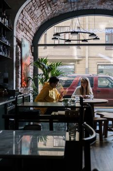 Two friends enjoying a casual meet-up in a cozy café with a classic brick archway.