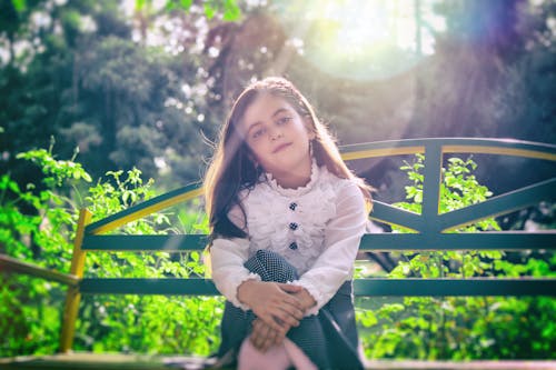 女孩坐在植物附近的長椅上