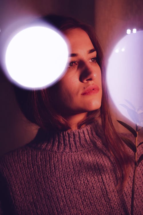 Wistful young ethnic lady in dark room looking away