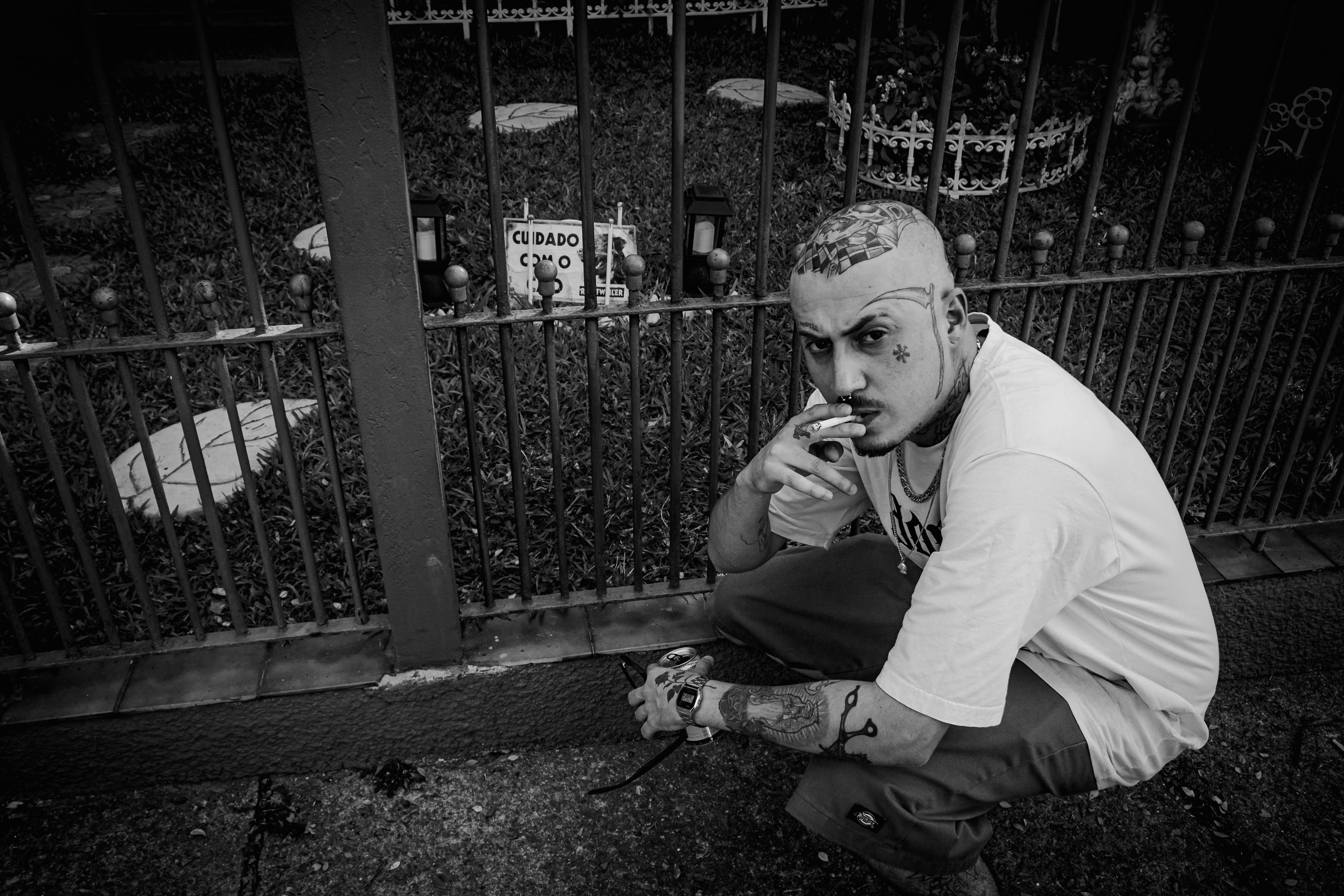 serious tattooed man smoking on street