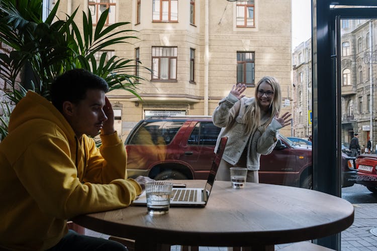 A Woman Looking At A Man Through The Window