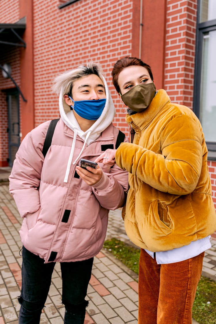 People In Face Masks Using Phone Outdoors