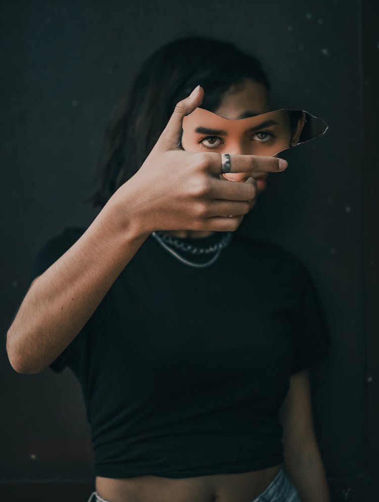 A Person Holding A Broken Mirror With Reflection Of A Person's Eyes