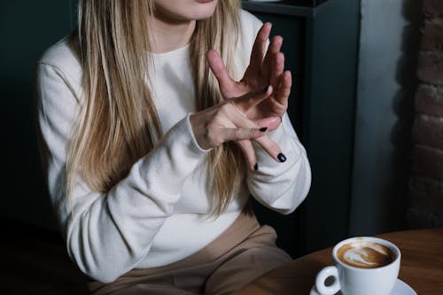 Free Woman in White Long Sleeve Shirt Doing Sign Language Stock Photo