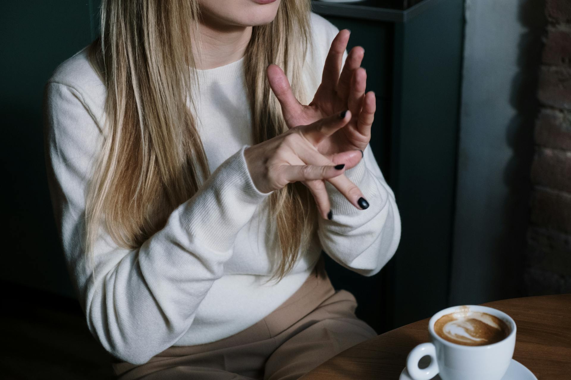 Woman in White Long Sleeve Shirt Doing Sign Language