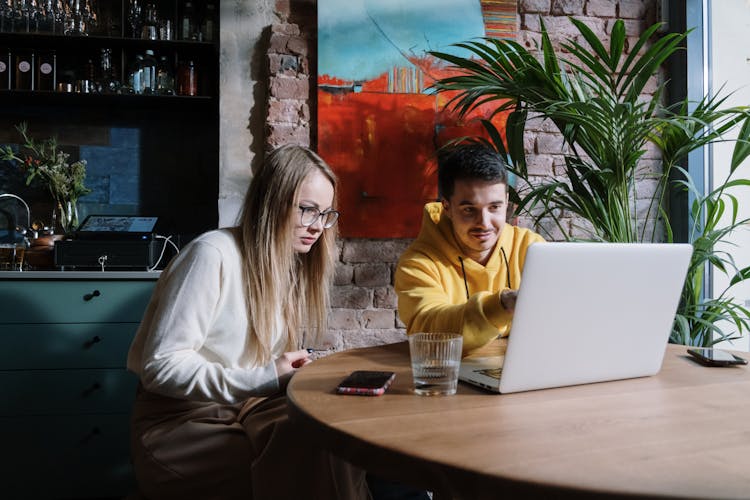 Man And Woman Sitting At Table Looking At Laptop