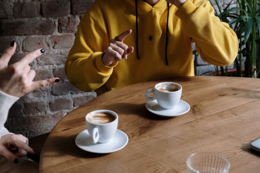 Person in Yellow Hoodie Holding White Ceramic Mug on Brown Wooden Table