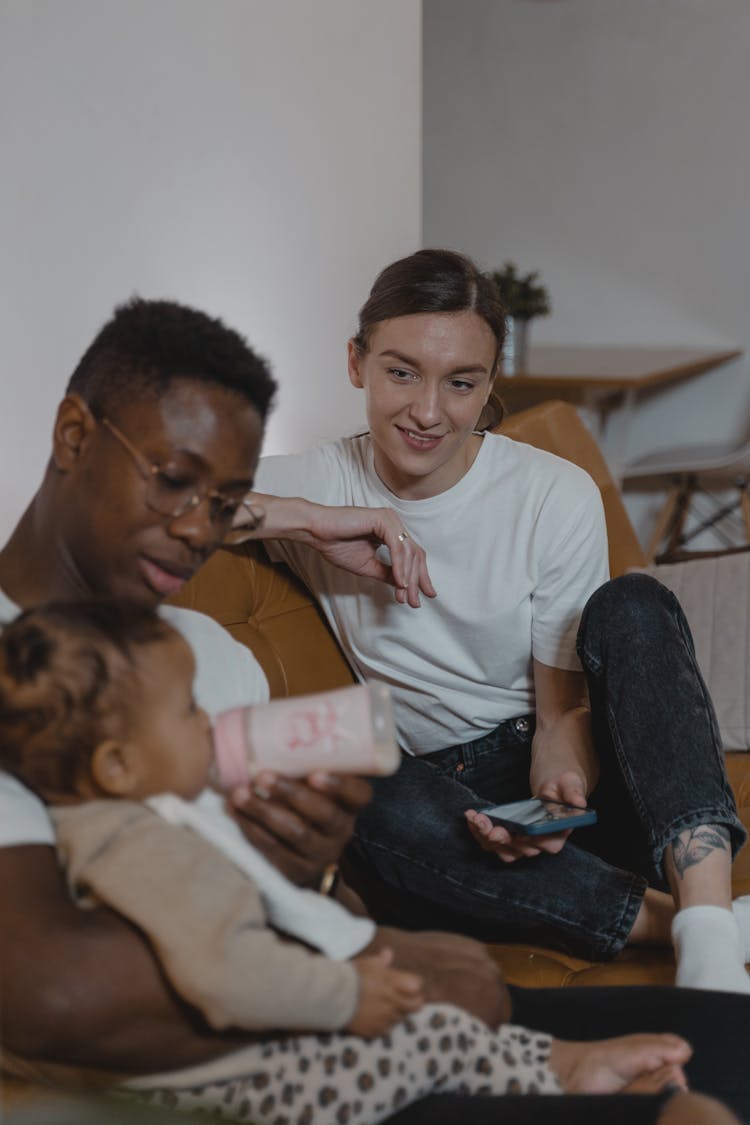 Woman In White Shirt Looking At A Man Feeding A Toddler