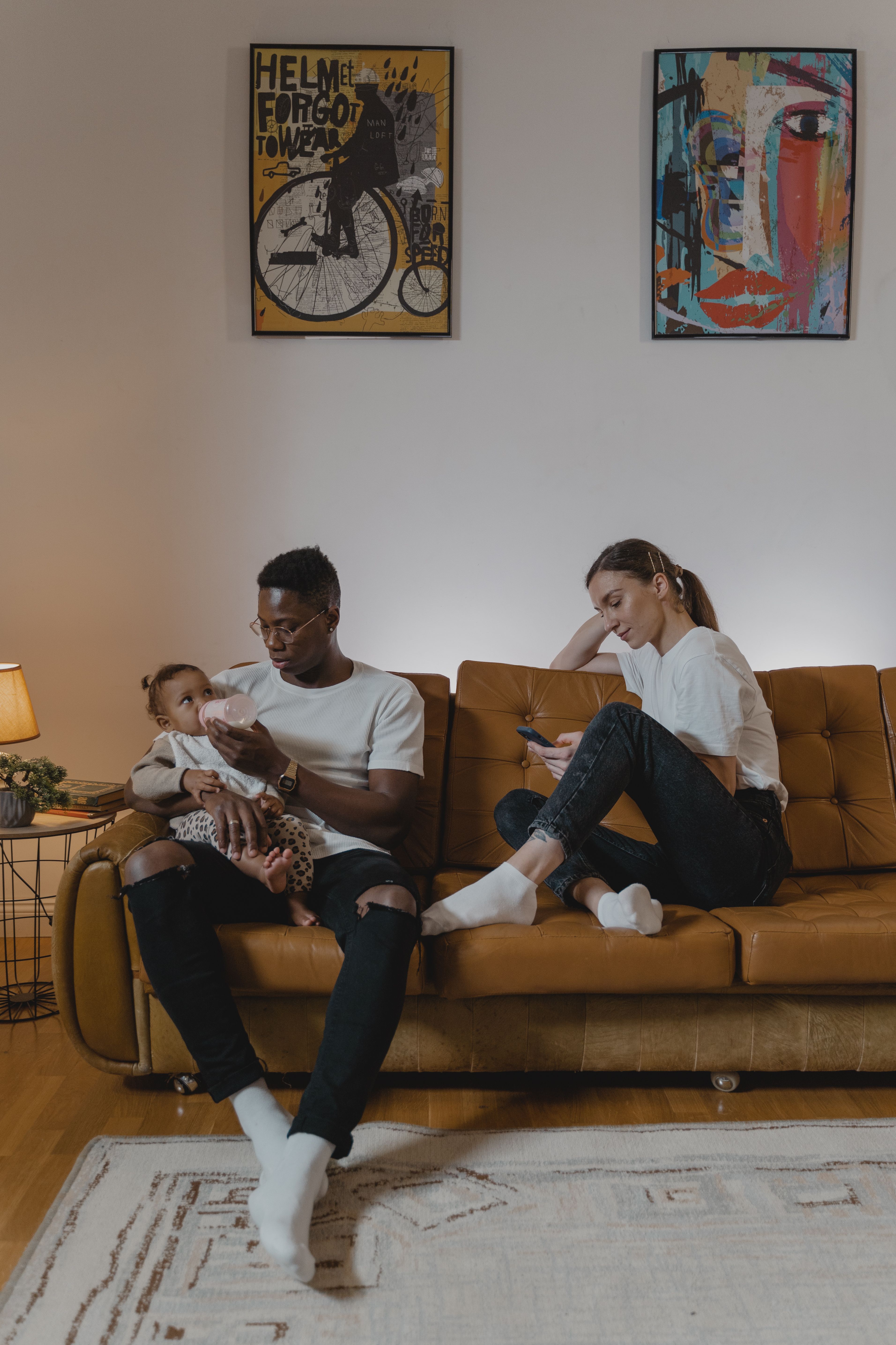 Family enjoying a relaxing moment on the couch, feeding a toddler in a cozy living room.