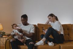 Family enjoying a relaxing moment on the couch, feeding a toddler in a cozy living room.