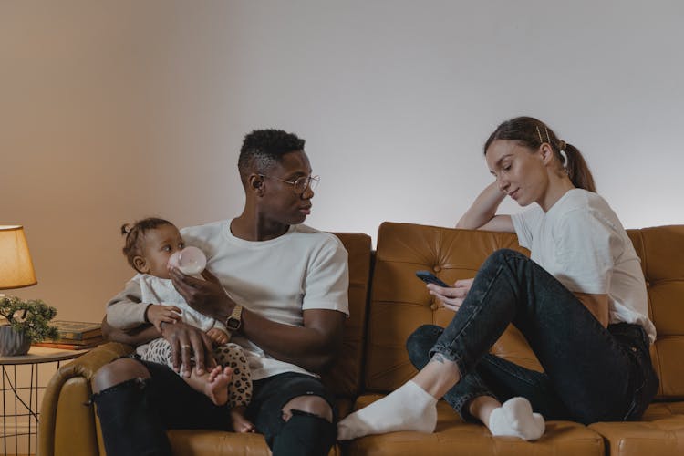 Man Feeding A Toddler While Talking To A Woman