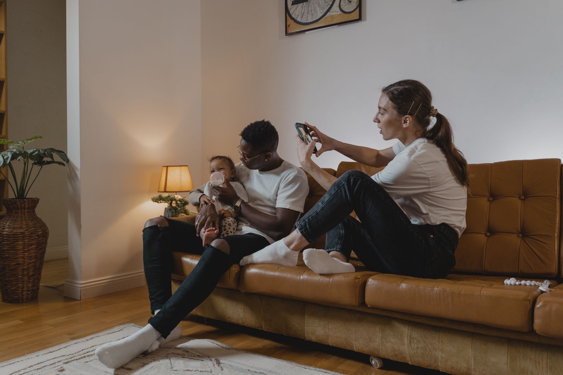 A family enjoying quality time with their baby on a cozy living room sofa.